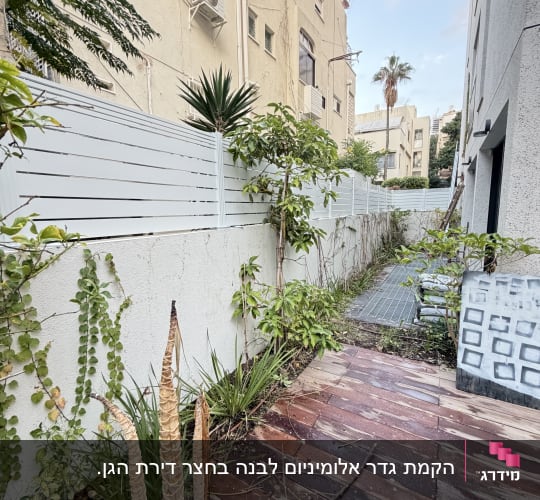 גדר לבנה עם צמחייה ליד בניין מגורים